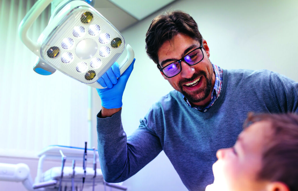 Dentist inspecting oral cavity of little boy